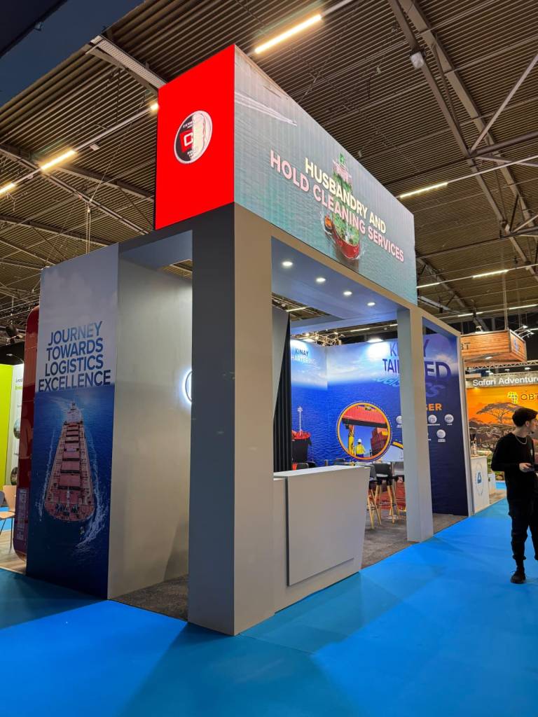 Container-themed breakbulk exhibition stand designed for KINAY, combining cargo logistics visuals, maritime-focused architecture, reinforced structural framing and turnkey design–production–installation by Quattro Stand.